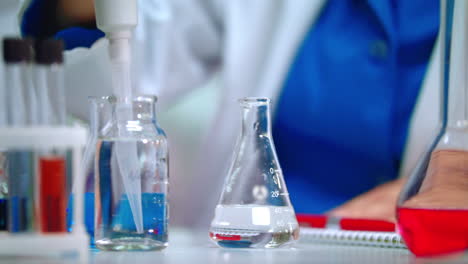 Laborarzt-Gießt-Transparente-Flüssigkeit-Mit-Pipette-In-Laborkolben